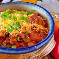 Slow Cooker Chili in a rustic ceramic bowl with cheese and green onions
