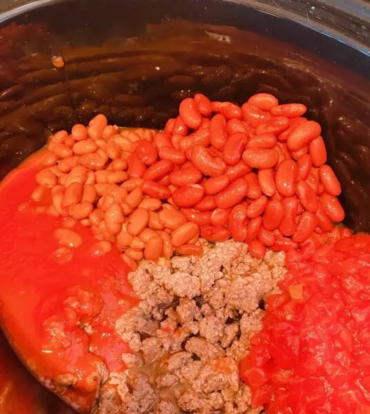 Slow cooker with ground beef, beans, and tomato products.