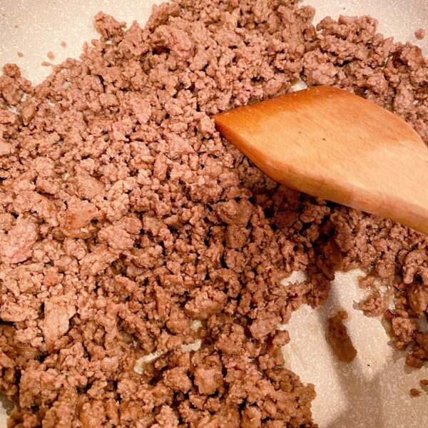 Large skillet on the stove top browning ground beef.