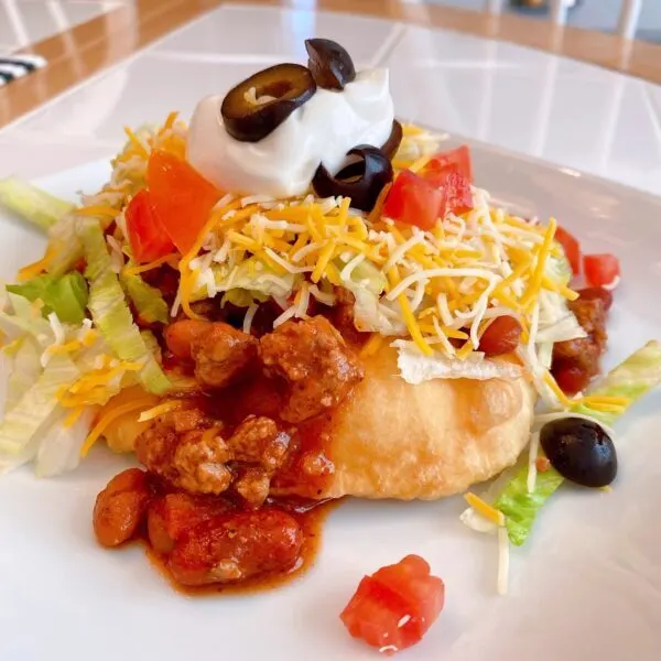 Navaho Fry Bread topped with slow cooker chili, cheese, lettuce, and all the taco fixings.