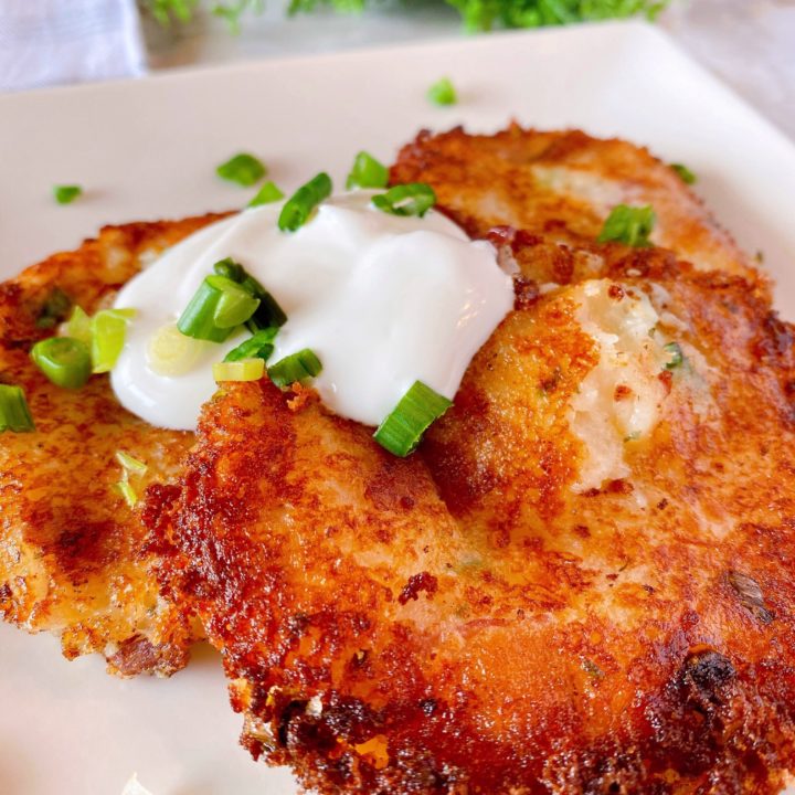 Loaded Mashed Potato Cakes on a plate with sour cream and chives