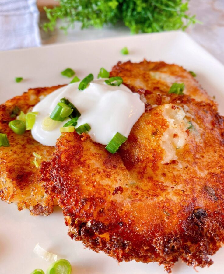 Loaded Mashed Potato Cakes on a plate with sour cream and chives