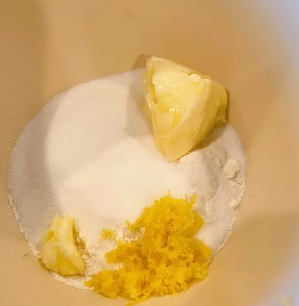 Lemon zest being added to topping ingredients in small bowl, ready to mix.