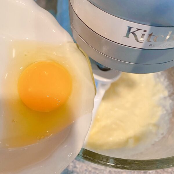 Adding eggs to the butter in the mixer.