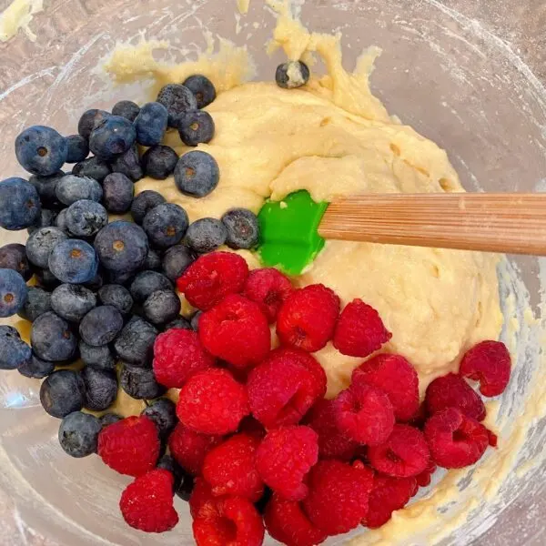 Adding 3/4 cup fresh raspberries, and fresh blueberries to muffin batter.