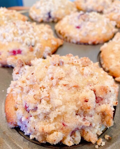 Close up photo of baked streusel topped mixed berry muffins in the muffin tin. Fresh out of the oven.