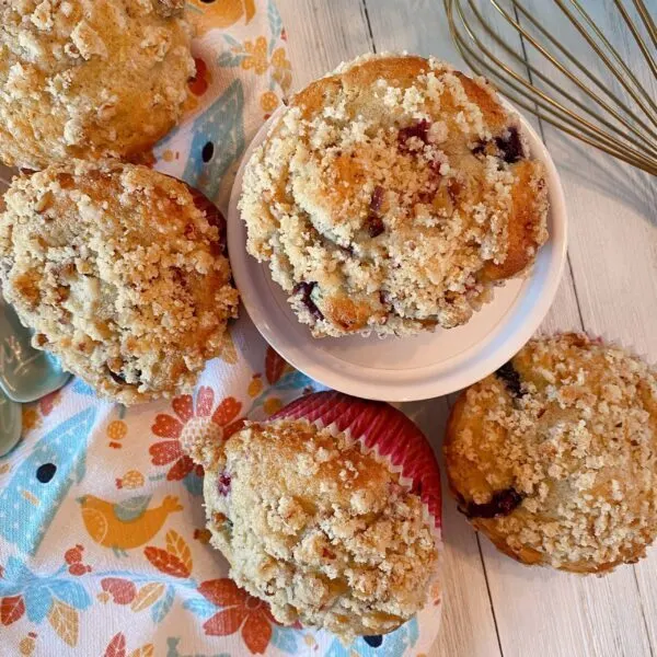 Overhead shot of pile of streusel topped mixed berry muffins on a white board.