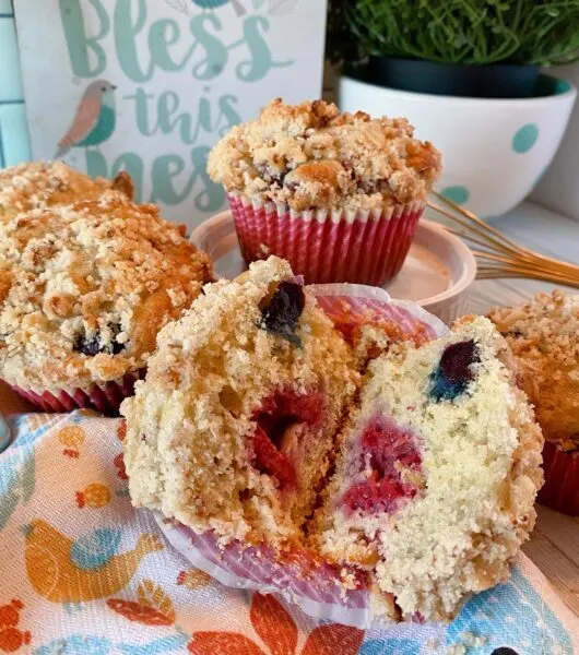 Streusel topped mixed berry muffins split open, on the table ready to eat.