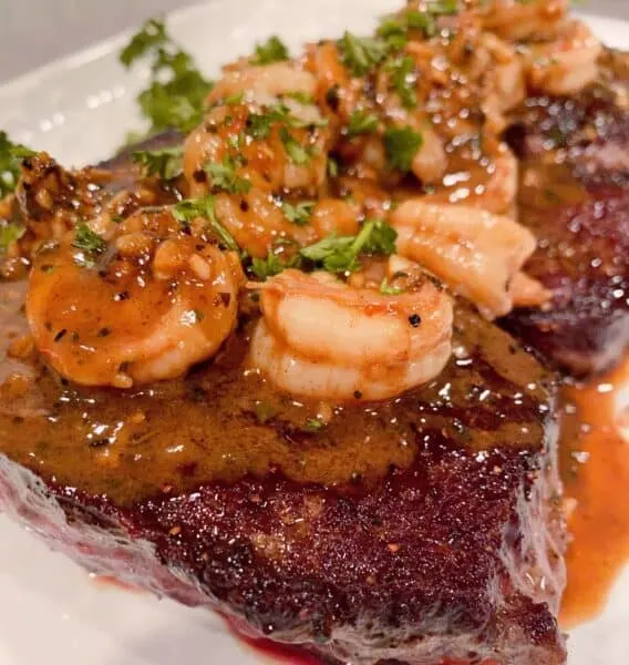 Denver Steaks on a platter with shrimp and red wine sauce