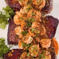 Denver Steaks with Shrimp and garlic herb sauce on a platter with parsley garnish