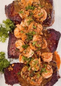 Denver Steaks with Shrimp and garlic herb sauce on a platter with parsley garnish