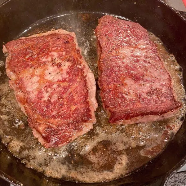 Two Denver steaks flipped over after being seared on the first side.