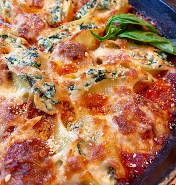 Baked Stuffed Pasta Shells and Meatballs with golden cheese and sauce in a large cast iron skillet
