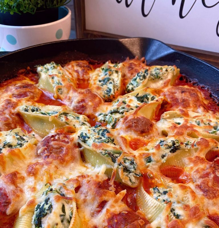 Spinach and Cheese stuffed Shells in a large cast iron skillet topped with golden brown cheese and a rich tomato sauce.