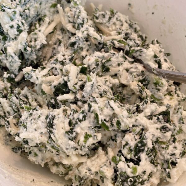 Bowl full of cheeses and spinach mixed until well blended.