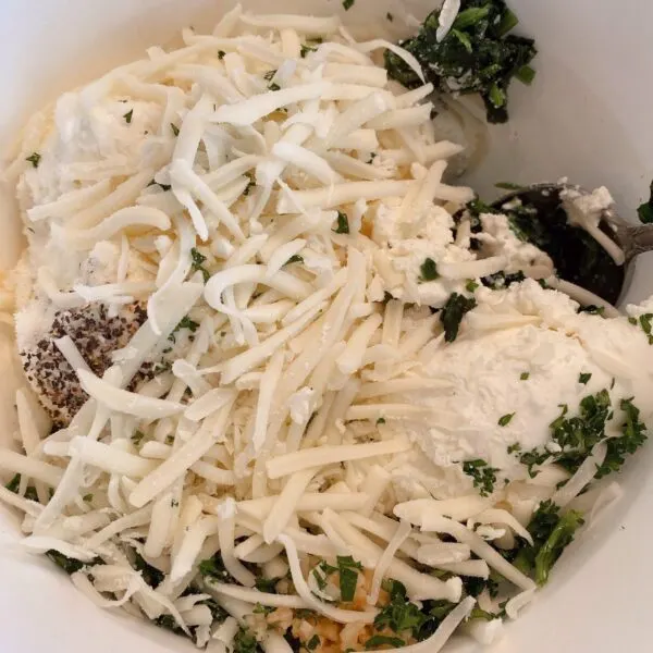 eggs, ricotta cheese, mozzarella cheese, Parmesan cheese, spinach, salt, pepper, and parsley in a bowl for shell filling.