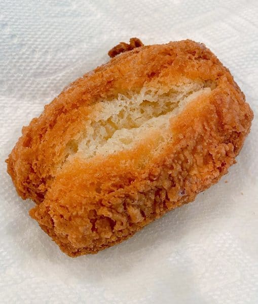 placing cooked donut on paper towel lined prepared cooling rack