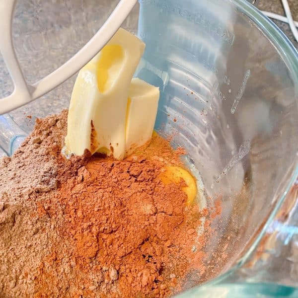 adding butter, vanilla, and eggs to cake mix in bowl of mixer