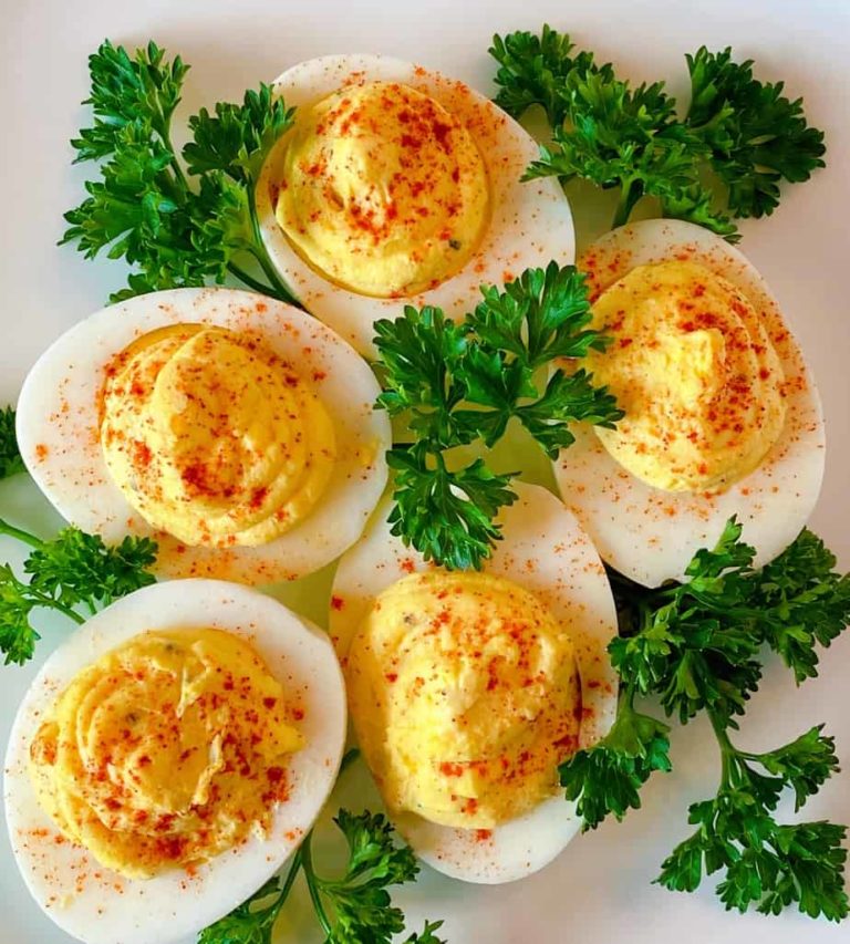 plate full of deviled eggs with parsley surrounding them.