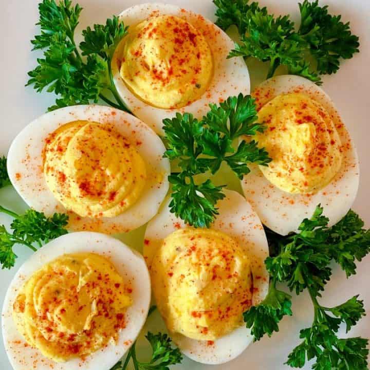 plate full of deviled eggs with parsley surrounding them.