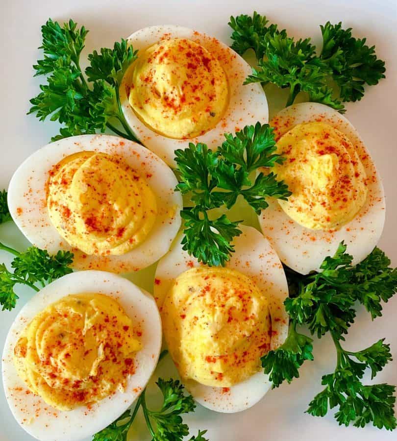 plate full of deviled eggs with parsley surrounding them.