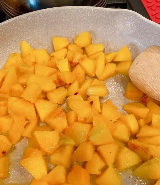 Diced peaches in a large skillet with butter
