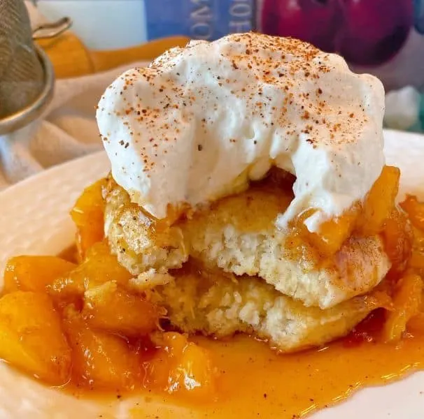 Fried Peaches and Biscuit on a dessert plate with a bite taken out.