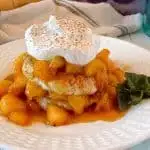 Fried Peach Sweet Biscuit Shortcakes on a plate with whipped cream and a sprig of mint