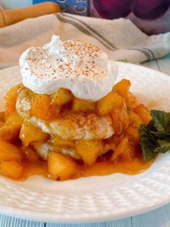 Fried Peach Sweet Biscuit Shortcakes on a plate with whipped cream and a sprig of mint