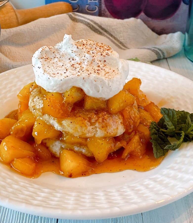 Fried Peach Sweet Biscuit Shortcakes on a plate with whipped cream and a sprig of mint