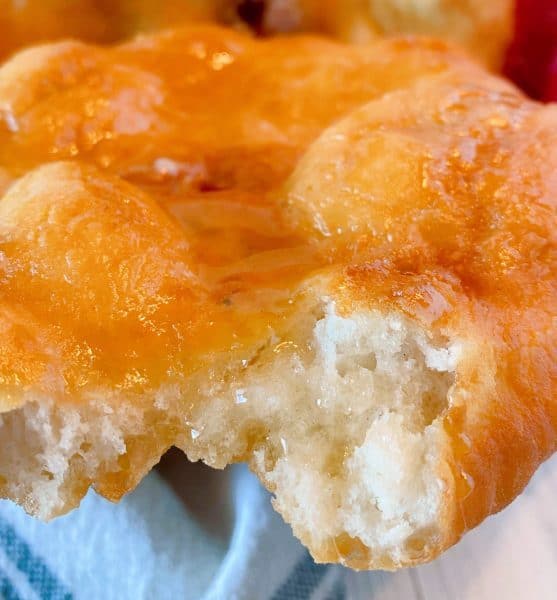 Piece of Indian Fry Bread with honey and butter and a bite eaten out of it to show the inside.