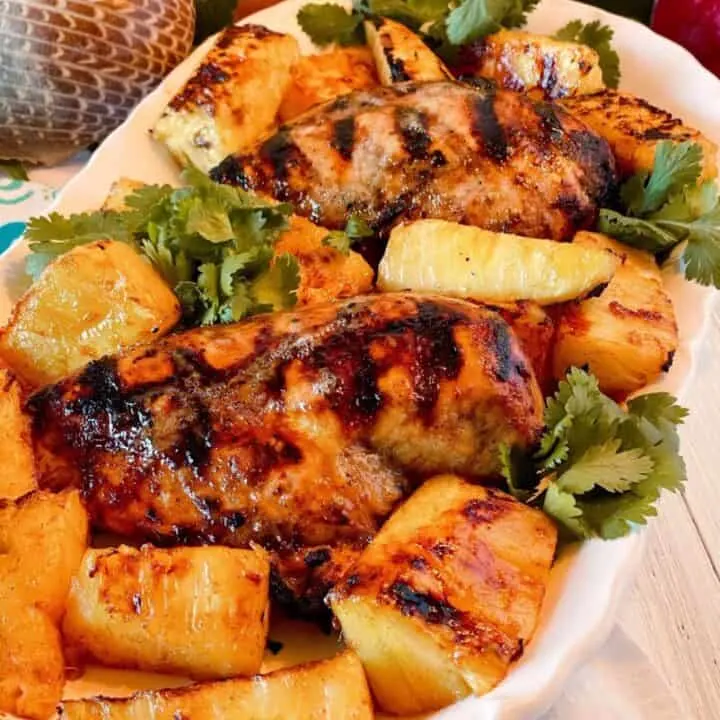 Close up photo of a platter filled Jerk chicken and grilled pineapple.