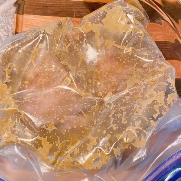 Chicken sealed in zip lock bag and in a bowl ready to be placed in the refrigerator.