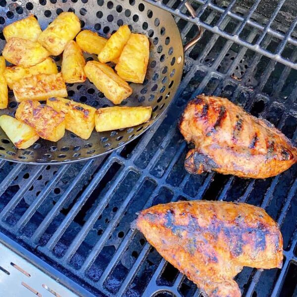 Chicken grilled on the BBQ with basket of grilled pineapple.