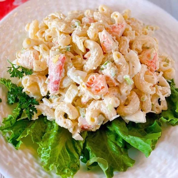 Close up photo of a plate full of the best seafood pasta salad on a bed of lettuce.