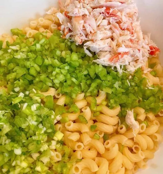 Bowl with cooked macaroni, chopped celery, onion, and crab meat.
