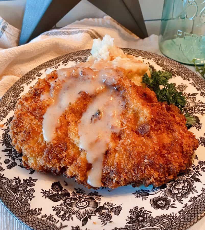 Chicken Fried Pork Steak on a plate with creamy gravy and mashed potatoes