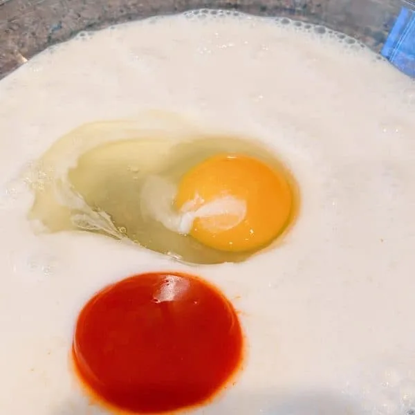 Pie dish with buttermilk, egg, and buffalo sauce