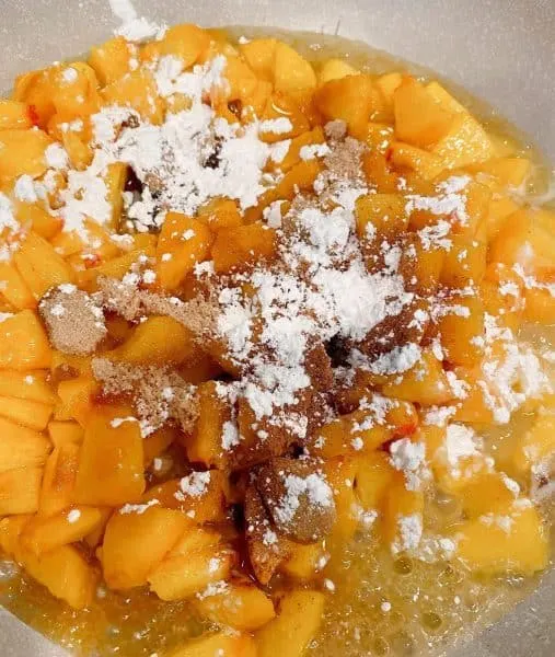 Adding cubed peaches to a skillet over medium high heat with cinnamon and corn starch