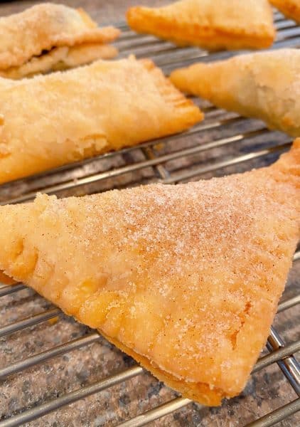 Hand pie dipped in cinnamon sugar and cooling on the rack.