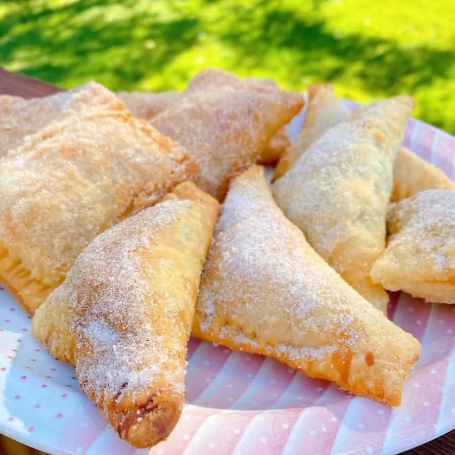 Plate filled with homemade fried peach hand pies coated in cinnamon sugar