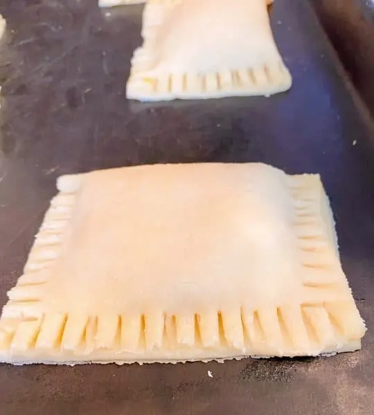 Fresh hand pie's made and ready to fry on a baking sheet.