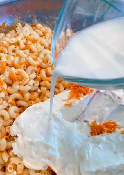 Adding mayonnaise and milk to the pasta.