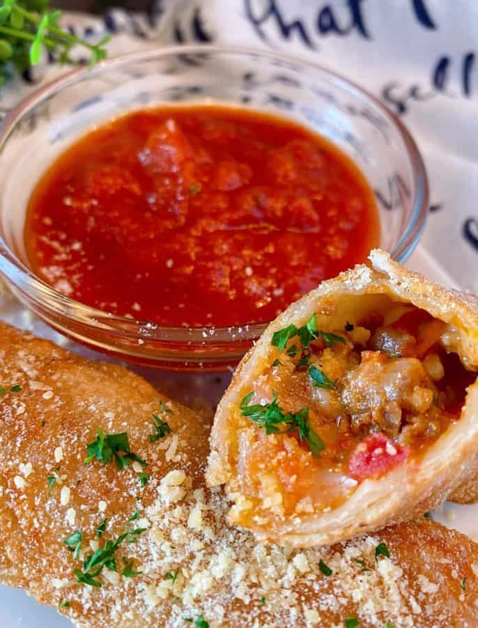 Homemade Pizza Rolls cut open on a table with marinara sauce for dipping