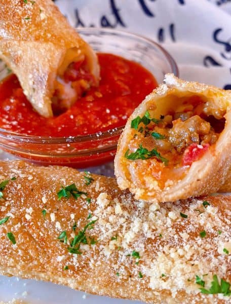 Egg roll cut open and served with marinara sauce.