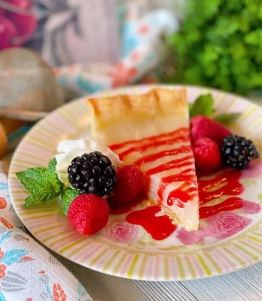 Slice of Water Pie with Raspberry sauce and fresh berries.