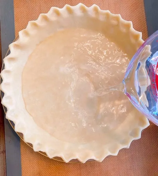 Pouring water into prepared pie crust.