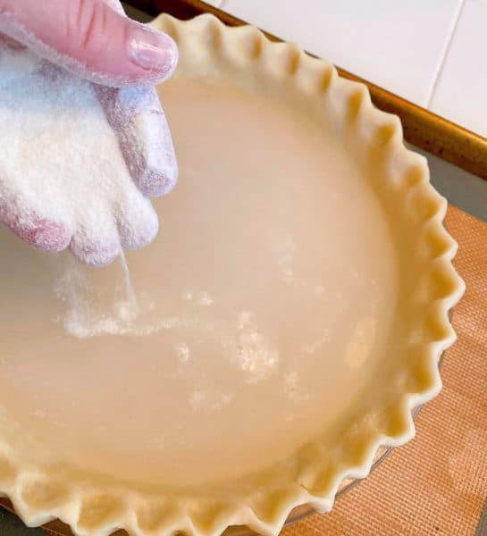 Sprinkling flour and sugar over the water in the pie crust