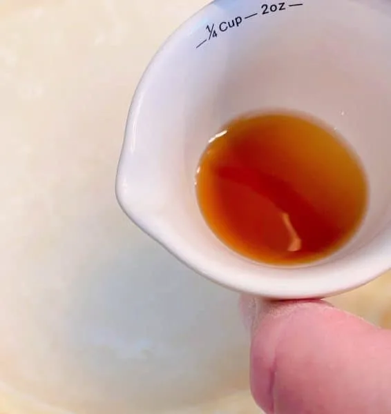 Vanilla extract in a small measuring cup sprinkled over water mixture of pie.