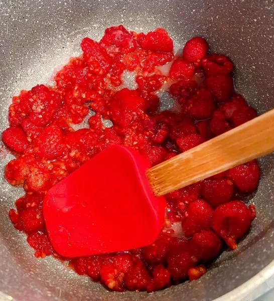 Fresh Raspberries in a small sauce pan being smashed for raspberry sauce.